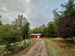 Gravel drive leads to cabin high above the pond.