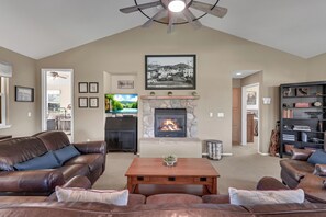 Living room with tall ceilings, large screen tv and propane fireplace.