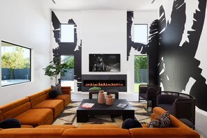 Professionally and intricately designed modern styled living area with large hand-painted mural, 20 ft vaulted ceilings, large electric fireplace, large smart TV, and complete with designer furnishings.