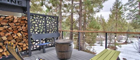 The back deck with a fire pit is ready for BBQ and cozy fires with stocked firewood and ample seating.