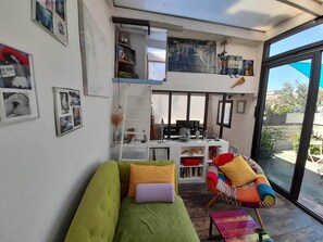 Le Salon Véranda : au fond la mezzanine chambre et en dessous l'espace bureau. 