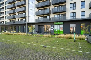 An exterior view of a modern residential building with a well-maintained facade, green landscaping, and clear pathways.
