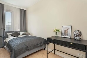 A cozy bedroom featuring a double bed with gray bedding, bedside tables, and a minimalist decor style.
