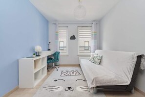 A cozy space with a small desk and sofa bed, decorated in soft blue tones, creating a multifunctional room.
