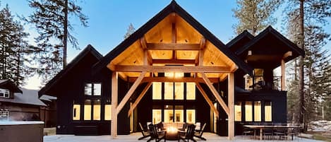 Back of home featuring outdoor dining table  heated covered seating area