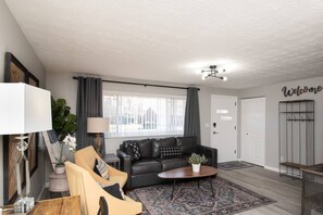 Large windows bring in natural light, enhancing the room’s inviting feel.