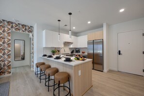 Fully equipped modern kitchen stocked with all culinary essentials and featuring stainless steel appliances with island bar seating.