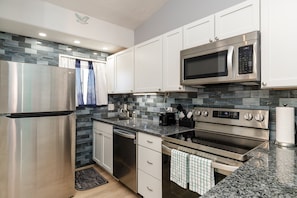 Fully equipped kitchen with new stainless steel appliances, counter tops and unique back splash