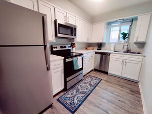 Featuring stunning stainless steel appliances and bright white cabinets, this space is designed for both chefs and homebodies alike.