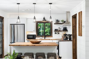 Large butcher block island separates a well-stocked kitchen and the dining space