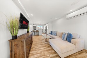 Cozy living area with a large sofa, flat-screen TV, and stylish wooden cabinet.