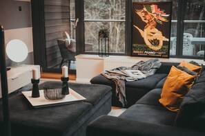 An elegant sofa, cozy lighting, and large windows overlooking greenery. A great place to relax after a day at the beach.