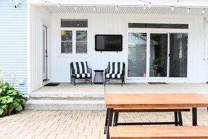 Inviting outdoor lounge area featuring comfortable seating and an entertainment hub with an outdoor TV, perfect for relaxation and gatherings."