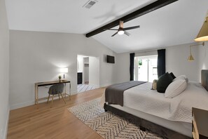 Primary bedroom has a king sized bed, smart plugs next to the bed, and a desk.