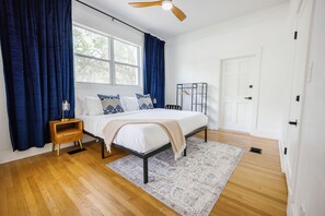 Spacious king bedroom featuring natural light, cozy linens, and blackout curtains for a restful night’s sleep.
